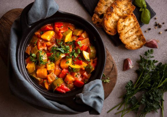 Cooked various vegetables with herbs in a black cooking pot