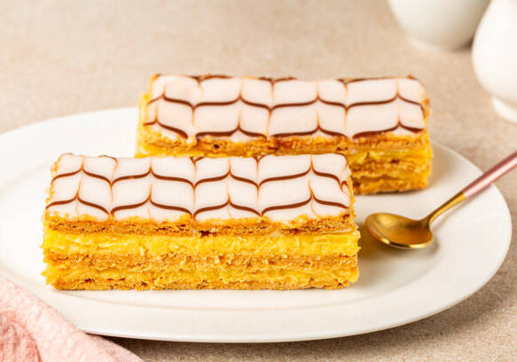 The mille-feuille, or millefeuille, is a piece of French pastry made from three layers of puff pastry and two layers of pastry cream. The top of dessert is iced with icing sugar.