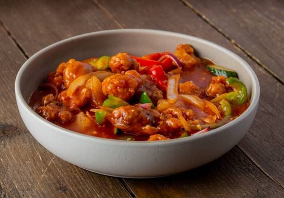 A bowl of delicious Sweet and sour on a wooden table