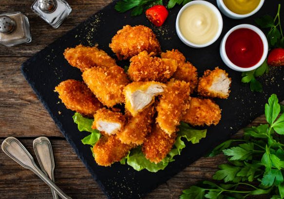 Seared chicken nuggets and ketchup on wooden background