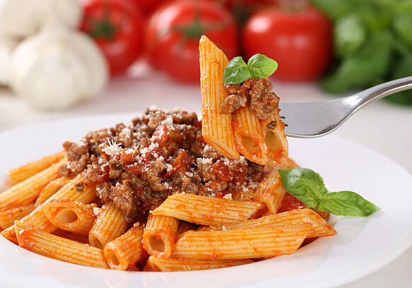 Eating pasta Bolognese or Bolognaise sauce noodles meal on a plate